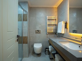 A modern bathroom with a glass shower enclosure, a toilet, a sink with a mirror, and a towel rack.