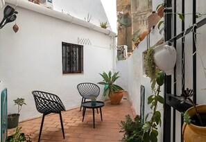 A small patio with two chairs, a table, and potted plants. - Studio 'Casa Bakara Estudio' with Mountain Views and Wi-Fi (Vejer de la Frontera)
