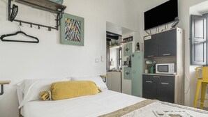 Une chambre comprenant un lit, un porte-manteau suspendu, un four à micro-ondes et un coin cuisine.
