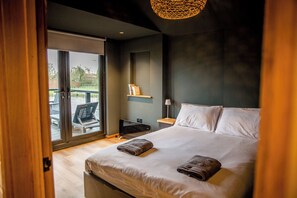 Une chambre avec un grand lit, un bureau, une chaise et une vue sur l’extérieur.