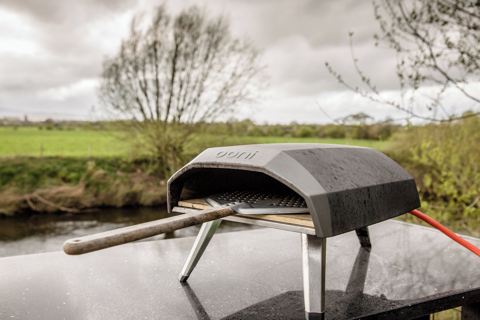 A portable oven on a vehicle with a grassy field and trees in the background.