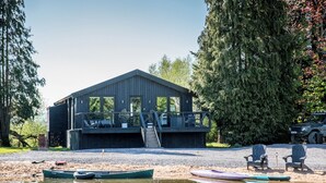 Une cabane dotée d’une terrasse, d’un espace salon extérieur et d’un quai avec des bateaux.