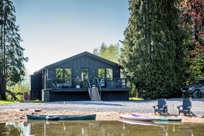 Una cabaña con terraza, mobiliario exterior y un muelle con barcos.