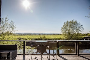 Un patio con una mesa y sillas, vistas a un campo verde y una masa de agua.