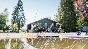 Un bâtiment doté d’un toit plat et d’une fenêtre bien visible, entouré d’arbres et bordé par une étendue d’eau.