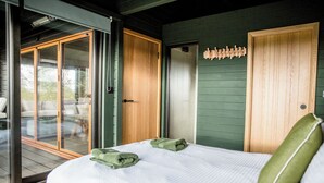 Une chambre avec un lit, un oreiller vert, une porte en bois et une vue à travers une porte vitrée.