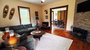 Una sala de estar con sofá, mesa de centro, chimenea y un comedor al fondo.