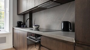 A modern kitchen with dark wood cabinets, a stainless steel countertop, and a black coffee maker.