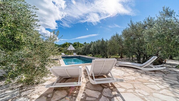 A pool area with two lounge chairs and a small umbrella.