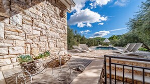 A stone building with a pool area, including lounge chairs and a pergola.