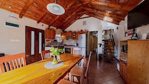 A spacious kitchen with wooden cabinets, a dining table, and a staircase leading to another level.