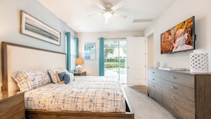 A bedroom with a bed, a nightstand, a dresser, a ceiling fan, a TV, and a door leading to a balcony. - 25% Off Encore Resort Arcade Home (Kissimmee)