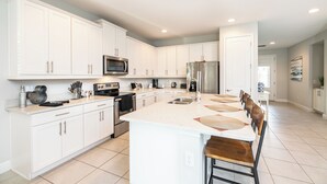 A spacious kitchen with white cabinets, a central island, and modern appliances. - 25% Off Encore Resort Arcade Home (Kissimmee)