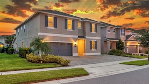 A two-story residential building with a driveway, front lawn, and a sunset sky. - 25% Off Encore Resort Arcade Home (Kissimmee)