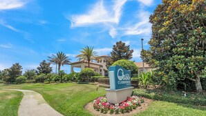 A sign for Oasis Clubhouse with a pathway leading to a building.