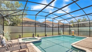 A covered outdoor swimming pool with lounge chairs and potted plants.