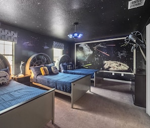 A bedroom with two bunk beds, each with a circular headboard and a Star Wars-themed pillow.