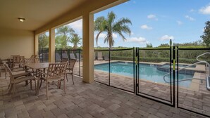 A covered patio with a pool, outdoor seating, and a view of palm trees. - 25% Off 10BR Encore Pool Villa Near DIsney (Kissimmee)