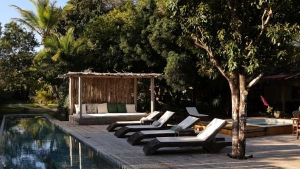 Un área de piscina con sillones de descanso y una cabaña pequeña.