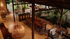 Un comedor interior con mobiliario de madera, lámparas de fibra y vista a un jardín.