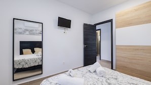 A hotel room with a bed, a TV mounted on the wall, and a wooden panel on the wall. - Cubo's Casa Rural Fernando Family Fun / private pools / air conditioning / free Wi-Fi (Cártama)