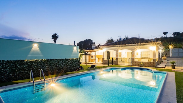 A swimming pool with a sunlit patio area, a covered seating area, and a well-maintained hedge. - Cubo's Casa Rural Fernando Family Fun / private pools / air conditioning / free Wi-Fi (Cártama)