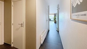 A hallway with a white door, a radiator, and a framed artwork on the wall. - Flat Zandloper - Side sea view in Oostduinkerke (Koksijde)