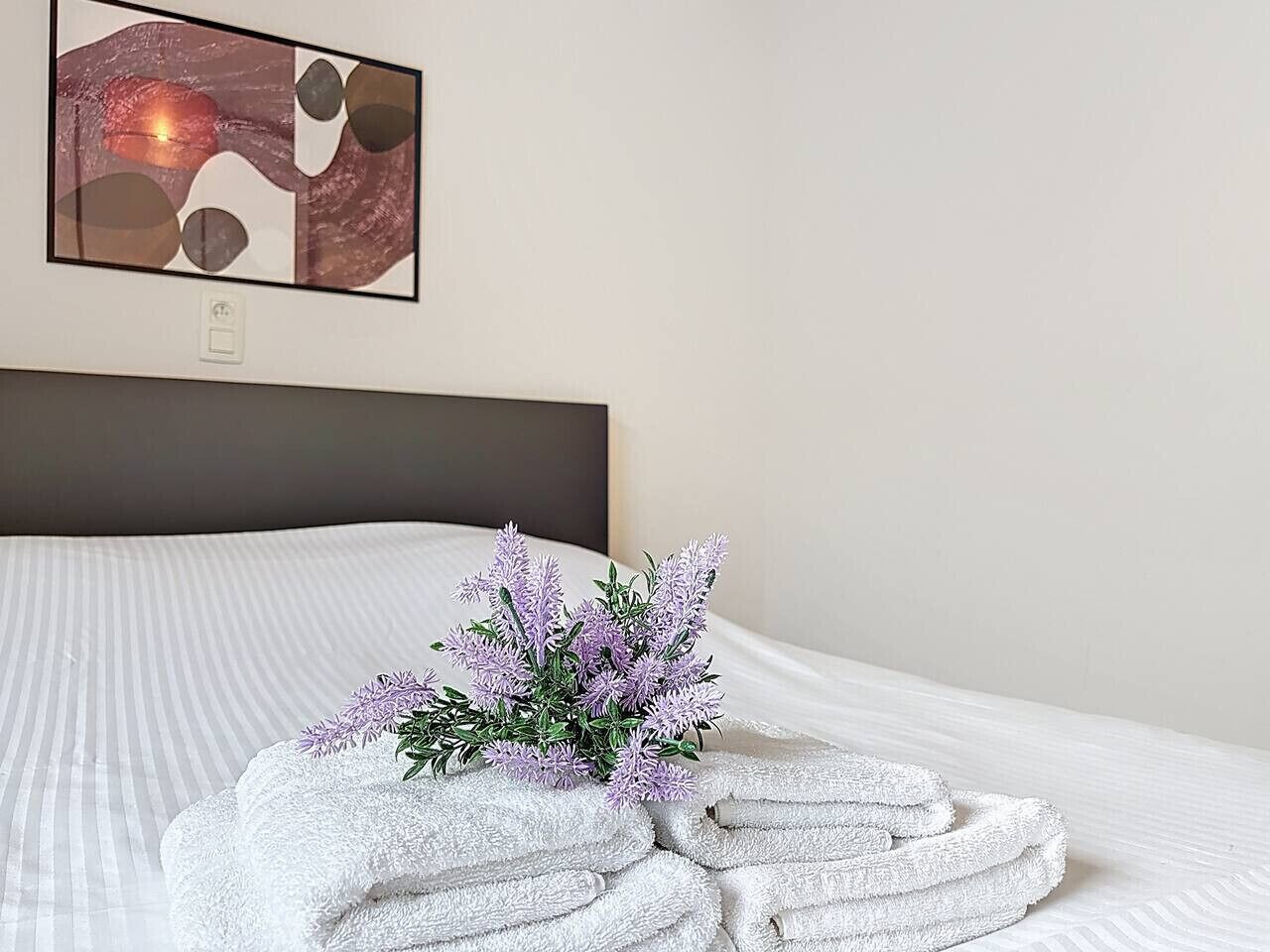 A neatly made bed with a floral arrangement and folded towels.