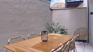 A wooden table with four wicker chairs and a black lantern in a corner.
