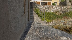 A stone staircase leading to a building with a stone wall and a metal railing.
