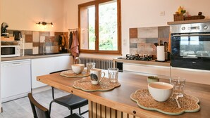 Una cocina moderna con una mesa de madera, horno integrado y ventana con vista a follaje.
