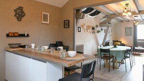 Una cocina con encimera de madera, armarios blancos y un comedor con mesa y sillas.