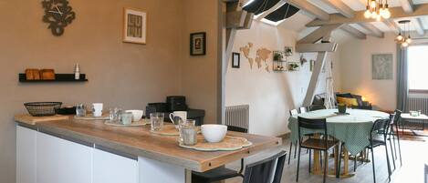 A kitchen with a wooden countertop, white cabinets, and a dining area with a table and chairs.