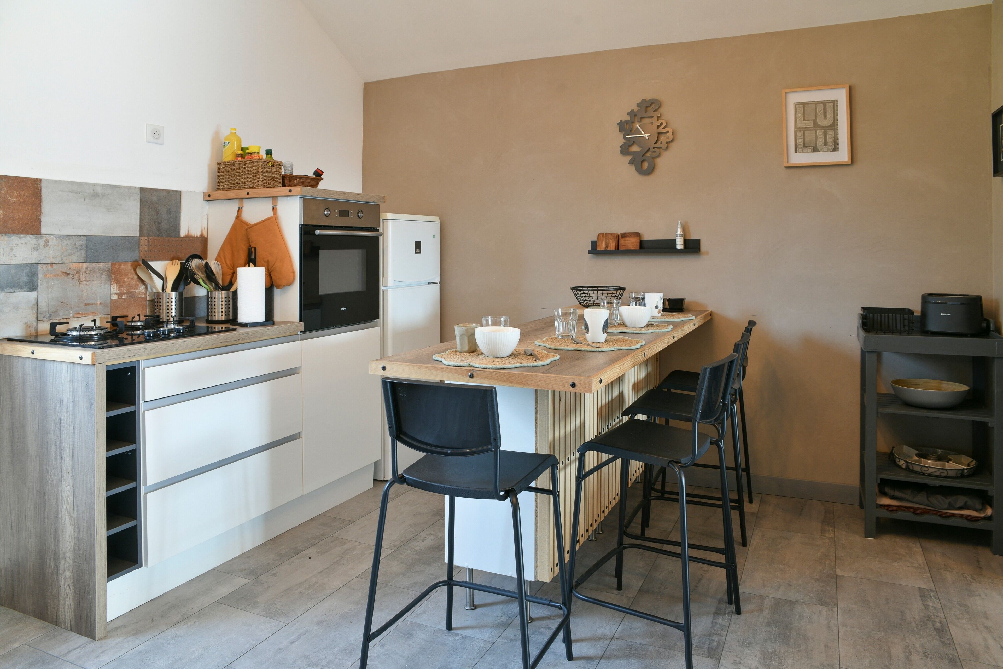 Una cucina moderna con un'isola centrale, sgabelli da bar, un piano cottura, forno e frigorifero.