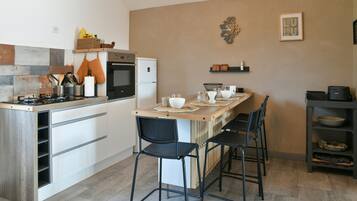 Una cucina moderna con un'isola centrale, sgabelli da bar, un piano cottura, forno e frigorifero.