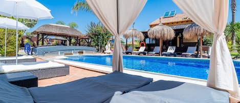 A poolside area with lounge chairs and a covered seating area.
