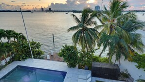 A pool area with a view of the water and palm trees. - Miami Stunning Waterfront Villa Escape (North Bay Village)