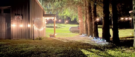 A building with a sign indicating it is a parking area, surrounded by trees and illuminated by string lights.