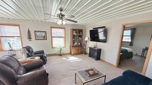 Un salon doté d’un ventilateur de plafond, d’un téléviseur, d’une cheminée et offrant une vue sur l’extérieur.