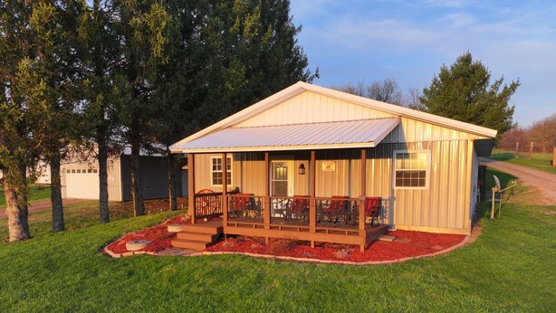 Une petite cabane en bois avec un porche, un garage et une pelouse bien entretenue.