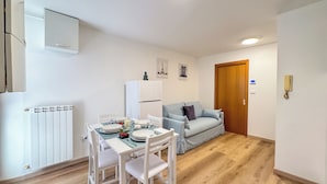 Een compacte leefruimte met een eethoek, een kitchenette en een bank.