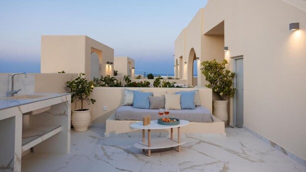 Eine Dachterrasse mit einer Couch, einem kleinen Tisch und Kübelpflanzen.