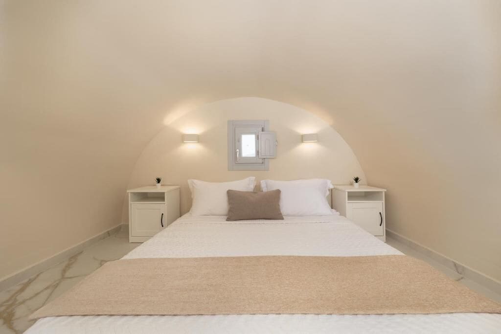 Un dormitorio con cama, mesitas de noche y una lámpara fijada a la pared.