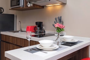Una encimera de cocina con una copa de vino, cuencos y un florero con flores.