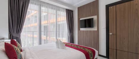 A modern bedroom with a large bed, a TV mounted on the wall, and a wardrobe.