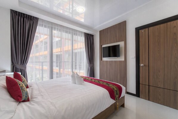 Une chambre moderne avec un grand lit, un téléviseur fixé au mur et une armoire.