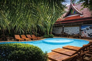 Un espace piscine avec des chaises longues en bois et une fresque murale.