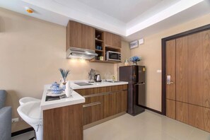 Cocina compacta con microondas, estufa y refrigerador.