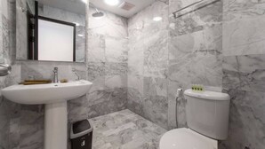 A bathroom with a white sink, mirror, and toilet, all set against marble walls. - Nara Condo 1br | Pool view | nbc nai harn (Rawai)