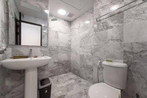 A bathroom with a white sink, mirror, and toilet, all set against marble walls. - Nara Condo 1br | Pool view | nbc nai harn (Rawai)